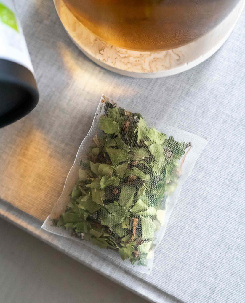 Close-up of BlissBlends I Need Calm herbal tea bag – holy basil, nanah mint, and bitter orange leaf in compostable, non-toxic cornstarch bag